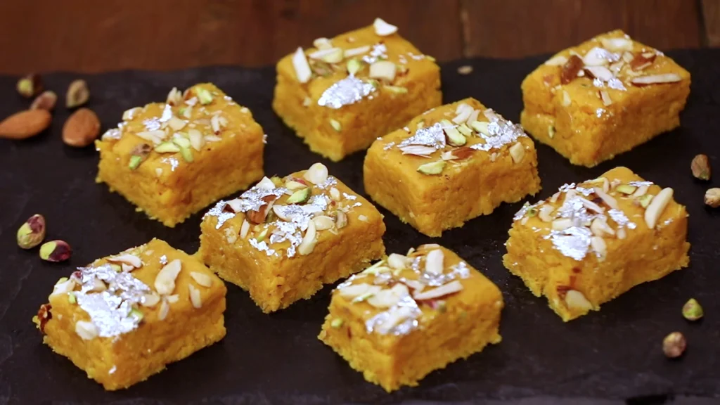 Celebrating Mango Season: The King of Fruits and Its Irresistible Dishes 6 Sliced mango coconut burfi with silver foil on top, ready to be served