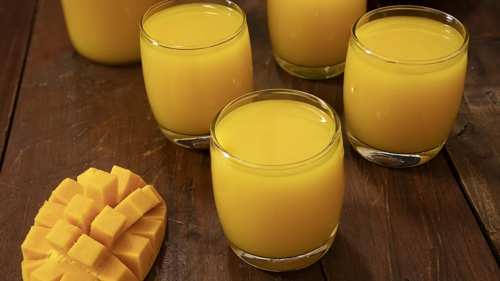 Celebrating Mango Season: The King of Fruits and Its Irresistible Dishes 5 Tall glasses filled with mango juice, condensation on sides